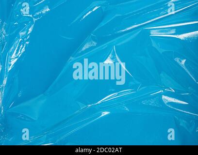 texture of a transparent stretching plastic film for packaging products on a blue background, full frame, close up Stock Photo