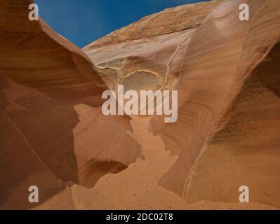 Fine sand in a small gorge with colorful striped rocks Stock Photo