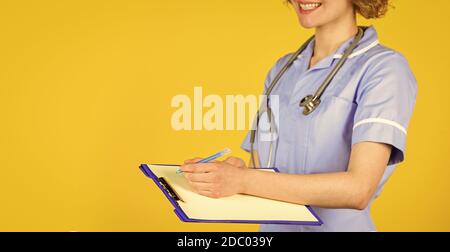 nurse in medical coat with documents writes important information. nurse writing some data into the folder of papers. Female hospital administrative in a modern medical center. copy space. Stock Photo