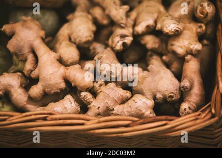 There are many ginger roots in a large square wicker basket. Harvest vegetables in the grocery store. Stock Photo