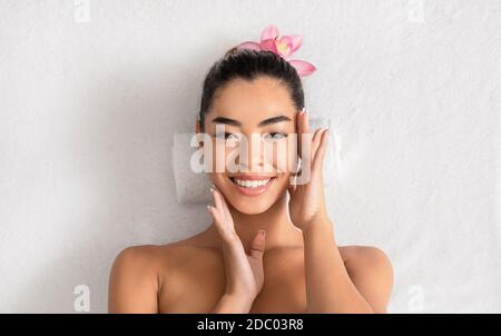 Asian Woman Lying On Massage Table In Spa, Enjoying Skin After Treatments Stock Photo