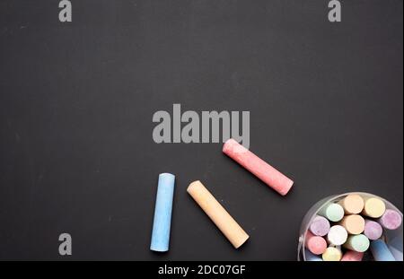 multicolored chalk in a plastic bucket on a black background, top view Stock Photo