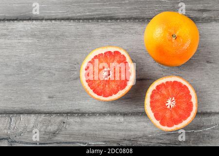 Table top view on red grapefruits, on cut in half, placed on gray wood desk. Stock Photo