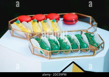 Group of french delicious colorful dessert Eclair on glass tray. Stock Photo