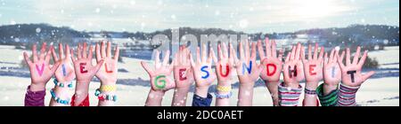 Kids Hands Holding Colorful German Word Viel Gesundheit Means Stay Healthy. Snowy Winter Background With Snowflakes Stock Photo