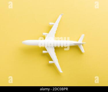 World Tourism Day, Top view flat lay of minimal toy model plane, airplane with copy space, studio shot isolated on a yellow background, accessory flig Stock Photo