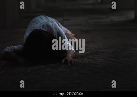 Girl zombie in blood. Asian Woman ghost with blood. Horror scary fear in dark house creepy crawling move slowly creeping out. Hair covering face her e Stock Photo