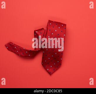 twisted silk red tie on red background, top view Stock Photo