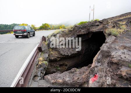 Sicily, Italy. A four-wheel drive vehicle drives past the entrance to the Grotta dei Tre Livelli (Cave of three levels), an easily-accessible lava cav Stock Photo