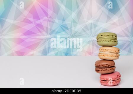 Closeup on a heap of four colorful macaron cookies on bright table isolated over abstract colored background. Template for your food and product displ Stock Photo