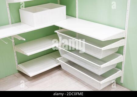 Empty white metal corner shelves for shoes in wardrobe, storage Stock Photo