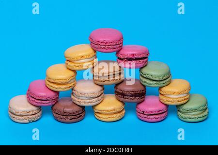 Macaron pyramids. Close-up of colourful French macaroons in shape of a pyramid on a blue background. Pastries, desserts and sweets. Macro. Stock Photo