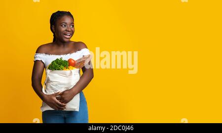 Excited black woman with peper bag of groceries looking at copy space Stock Photo