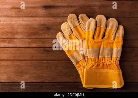 Close up of yellow safety protective gloves on wooden background Stock Photo
