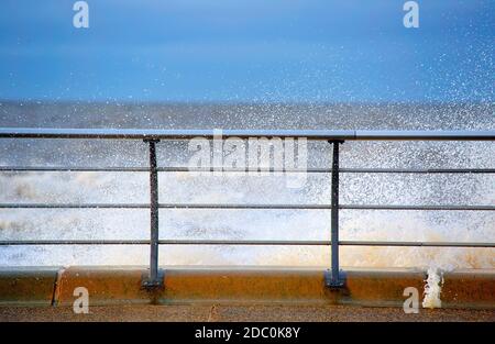 Wave breaking over curved strong metal railings on Blackpool seafront at high tide in winter Stock Photo