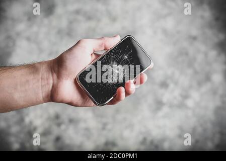 Smart cell phone with a broken screen in hand Stock Photo