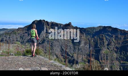 A woman standing on the mountain peak of Pico Ruivo, looking to Pico do Arieiro with its radar station. Madeira, Portugal. Stock Photo