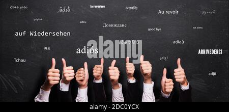 many thumbs up and blackboard with message GOODBYE in different languages Stock Photo