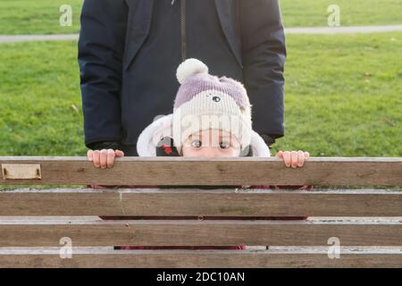A toddler on a bench in a park. Stock Photo