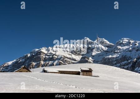 Small mountain huts on an alp in front of the Saentis massif in winter, Canton Appenzell-Ausserrhoden, Switzerland Stock Photo