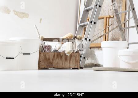 Indoor shot close up frontal view of bricklayer, plasterer or house painter tools on white floor with buckets in home renovation site Stock Photo