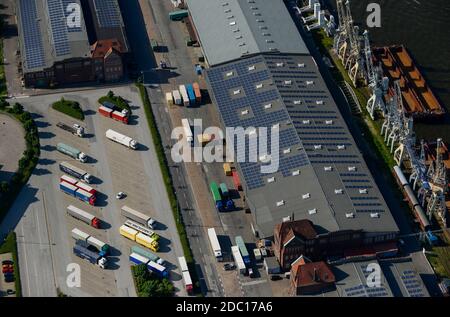 GERMANY Hamburg, photovoltaic panel of company Hamburg Energy on roof of harbour store building No. 50-52, trucks parking at wharf store house / DEUTSCHLAND Hamburgs groesste  Photovoltaik Anlage auf dem Kaischuppen 50-52 im Hamburger Hafen, Betreiber ist der staedtische Energieversorger Hamburg Energie, die 30.000 Quadratmeter Dachflaeche werden von Stiftung Hamburg Maritim gepachtet Stock Photo