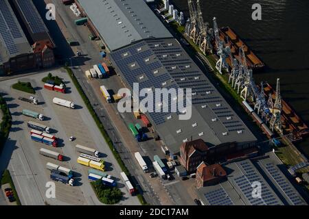 GERMANY Hamburg, photovoltaic panel of company Hamburg Energy on roof of harbour store building No. 50-52, trucks parking at wharf store house / DEUTSCHLAND Hamburgs groesste  Photovoltaik Anlage auf dem Kaischuppen 50-52 im Hamburger Hafen, Betreiber ist der staedtische Energieversorger Hamburg Energie, die 30.000 Quadratmeter Dachflaeche werden von Stiftung Hamburg Maritim gepachtet Stock Photo