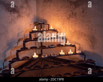 Small Tea lights on a metal stand inside a church Stock Photo