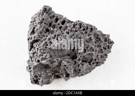 closeup of sample of natural mineral from geological collection - rough black Pumice rock on white marble background Stock Photo