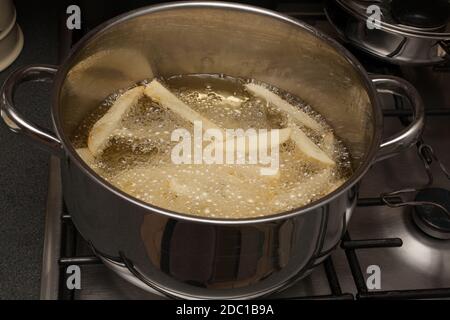 Homemade potato chips frying in a pan of hot oil Stock Photo