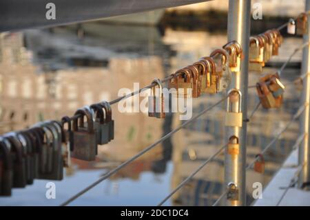 Rusty love Padlocks hanging on a iron wire on the sea water background.Many padlocks of lovers hanging on bridge railings. Stock Photo