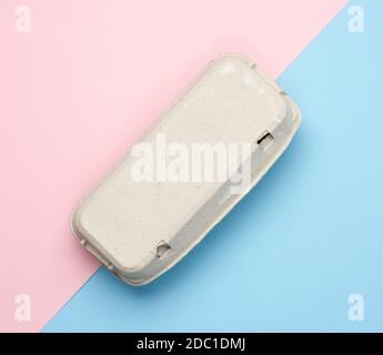 closed paper rectangular tray for chicken eggs on pink blue background, top view Stock Photo
