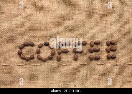 The word coffee made from coffee beans on sackcloth next to coffee beans Stock Photo