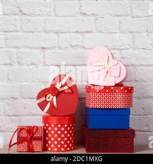 stack of various boxes with gifts on white brick background, festive backdrop Stock Photo