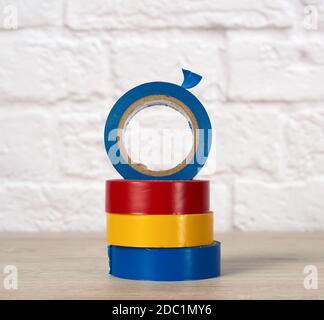 stack of colorful insulating tape on white brick wall background, close up Stock Photo
