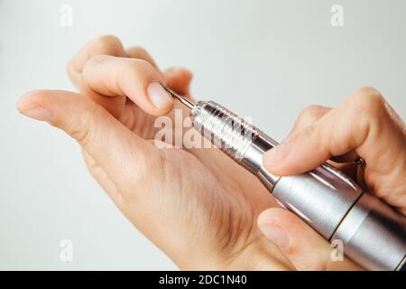 Image of the work of a manicure master. The manicure machine or manicure milling cutter close-up cuticle remover. Stock Photo