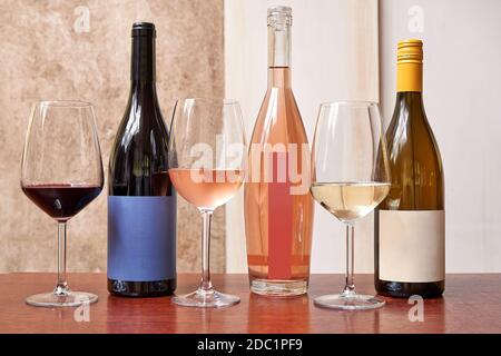 Three different kind of bottles of wine and three glasses against textured background Stock Photo