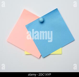 stack of colorful stickers pinned by blue button on white background, close up Stock Photo