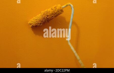 In motion paint roller against the orange wall Stock Photo