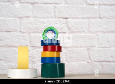 stack of colorful insulating tape on white brick wall background, close up Stock Photo