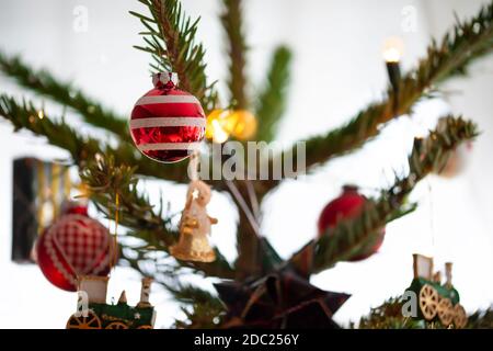 Decorated Christmas tree, real Nordmann fir in front of blurred background. Macro photography shows different pendants, angel, locomotive, gift, balls Stock Photo
