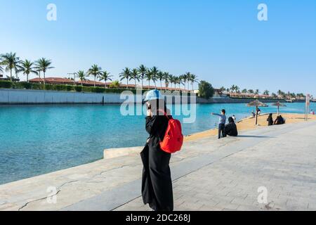 A Female tourist with red backpack wearing hijab in Jeddah Corniche, 30 km coastal resort area of Jeddah city, Saudi Arabia Stock Photo