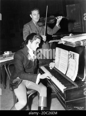 TYRONE POWER plays piano on set candid with accompaniment by Norma Shearer's mood music violinist SIGMUND SAXS during filming of MARIE ANTOINETTE 1938 director W.S. VAN DYKE Metro Goldwyn Mayer Stock Photo