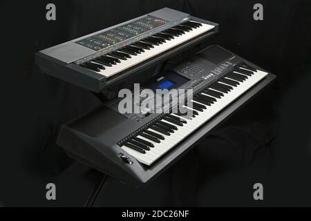Studio shot of two Yamaha electronic keyboards; Model PSR 70 (top) and PSR EW400, on a folding, metal  X-frame stand. Stock Photo