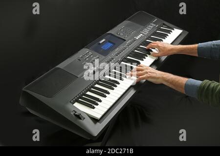 Studio shot of a Yamaha electronic keyboard being played; Model PSR EW400 on a folding, metal  X-frame stand. Stock Photo