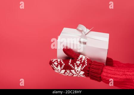 cropped view of woman in mittens holding present isolated on red Stock Photo