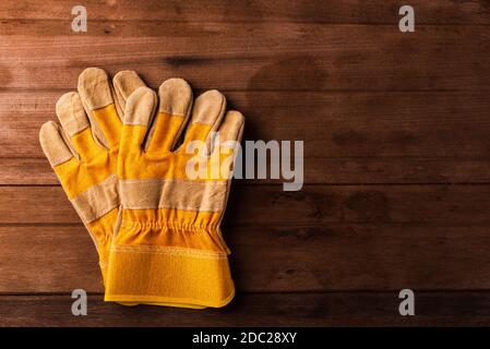 Close up of yellow safety protective gloves on wooden background Stock Photo