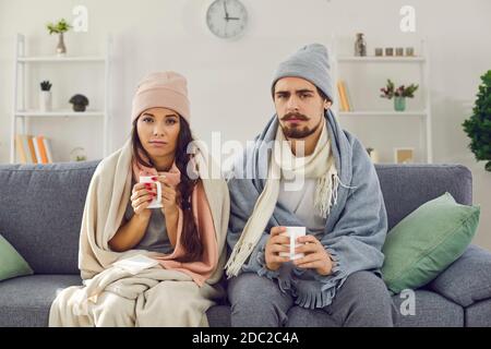 Upset young couple having problem with central heating or suffering from cold or flu Stock Photo