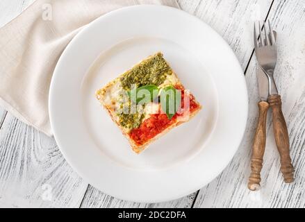 Portion of lasagne topped with tomato sauce and pesto Stock Photo