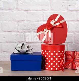 stack of various boxes with gifts on white brick background, festive backdrop Stock Photo